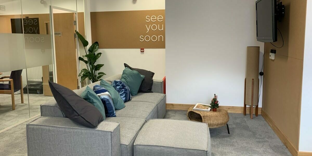 The interior of Community Venture's Stockton office, including wall mounted TV, sofas and plants.